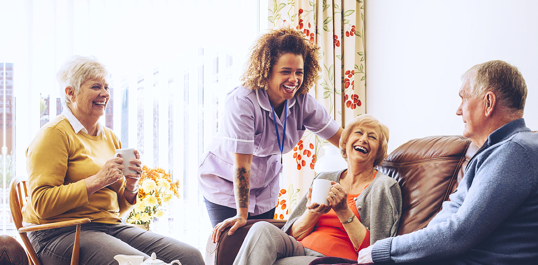 caregiver and three elders smiling